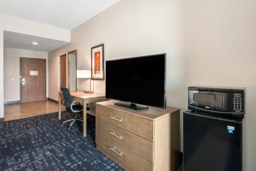 a hotel room with a flat screen tv and a desk at Comfort Suites Fort Lauderdale Airport & Cruise Port in Dania Beach