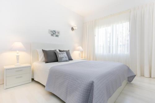 Litoral Mar Dream 17, beach front, free Wi-fi, private parking, pool في بورتيماو: غرفة نوم بيضاء مع سرير أبيض ونافذة
