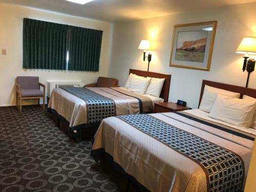 a hotel room with two beds and a chair at Canyonlands Motor Inn in Monticello