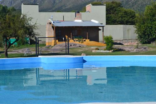 een zwembad met een huis op de achtergrond bij Cabañas Los Relinchos in Capilla del Monte