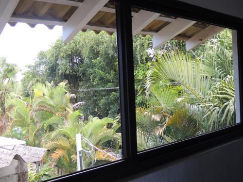 a window with a view of a forest at Flat Camburi in Camburi