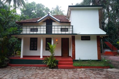 a white house with a red staircase in front of it at Orchid Trails Resort in Sultan Bathery