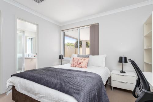 a white bedroom with a large bed and a window at Ardross Short Stays in Perth