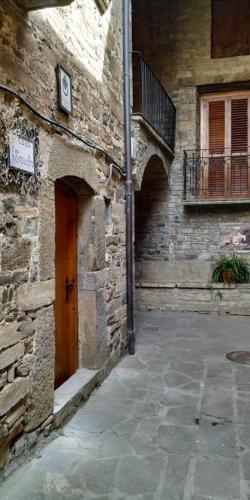 a stone building with a wooden door and a balcony at Casa Encuentra, en el Pirineo al lado de Ainsa in El Pueyo de Araguás