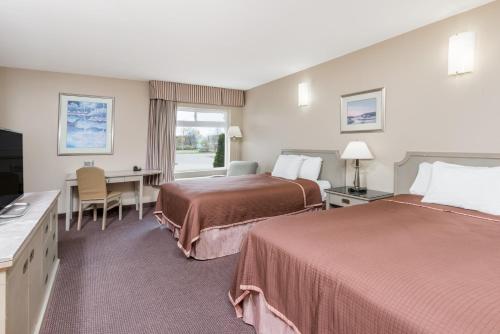 a hotel room with two beds and a desk at London Travel Inn in London