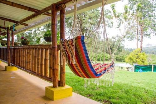 a hammock hanging from a porch of a house at Campground Hostal La Bonanza Chez Kika in Piendamó