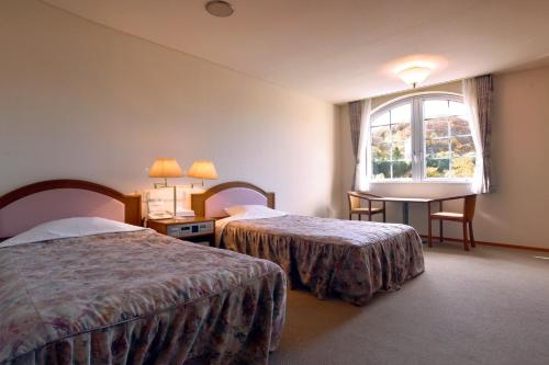 um quarto de hotel com duas camas e uma janela em Takinoue Hotel Keikoku em Takinoue