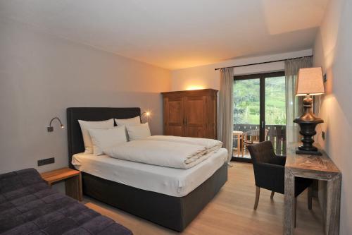 a bedroom with a bed and a couch and a window at Pension Hauenstein in Lagundo