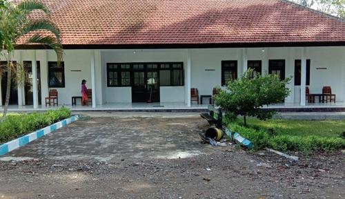 a woman standing outside of a house with a building at Sukamade Adventure Tour Package in Banyuwangi