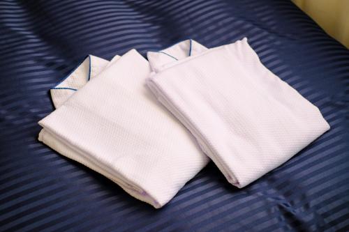 two white towels sitting on top of a bed at Hotel Grandolce HAKATA in Fukuoka