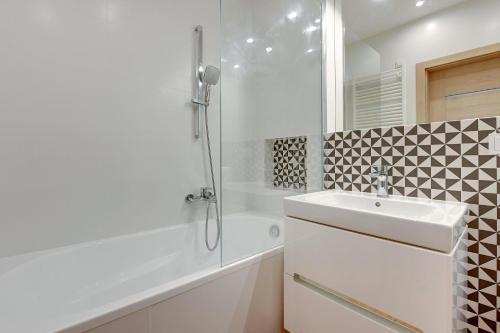a white bathroom with a sink and a shower at TriApart Nova Grobla 3 in Gdańsk