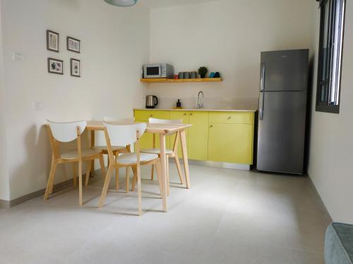 una cucina con tavolo, sedie e frigorifero di Kurlender Guest House a Sheʼar Yashuv