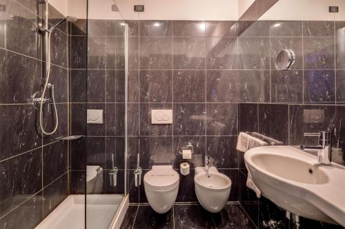 a black tiled bathroom with a toilet and a sink at Best Western Plus Royal Superga Hotel in Cuneo
