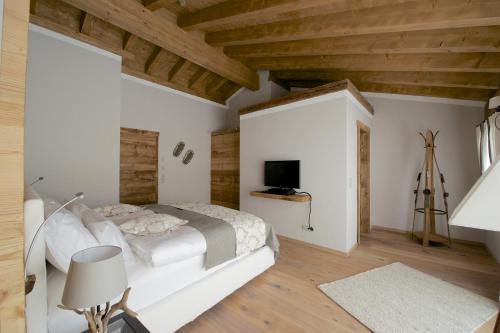 a white bedroom with a bed and a television at Hotelino Petit Chalet in Celerina