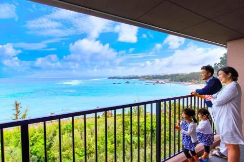 a family standing on a balcony with a view of the beach at Umino Ryotei Okinawa Nakamasou in Onna