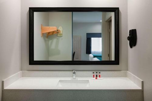 a bathroom with a sink and a mirror at Americas Best Value Inn Houston Willowbrook in Houston