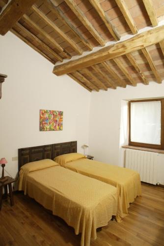 two beds in a white room with wooden floors at Podere Il Tigliolo in Castiglione dʼOrcia