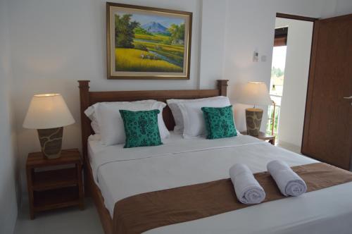 a bedroom with a large white bed with pillows at Askara Guest House & Hostel in Ubud
