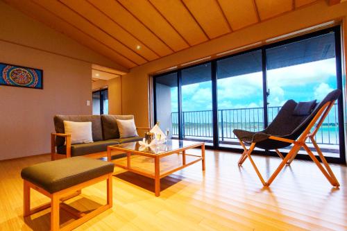 a living room with a couch and a chair and a table at Umino Ryotei Okinawa Nakamasou in Onna