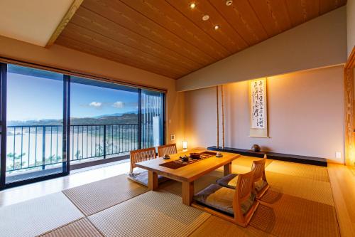 a dining room with a table and a large window at Umino Ryotei Okinawa Nakamasou in Onna