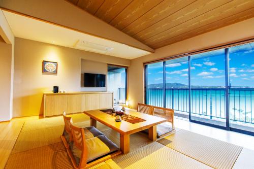 a dining room with a table and a view of the ocean at Umino Ryotei Okinawa Nakamasou in Onna