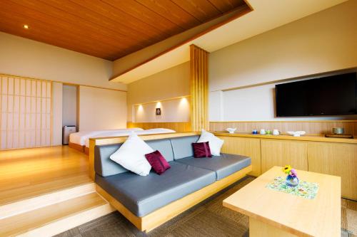 a room with a couch and a bed and a tv at Umino Ryotei Okinawa Nakamasou in Onna