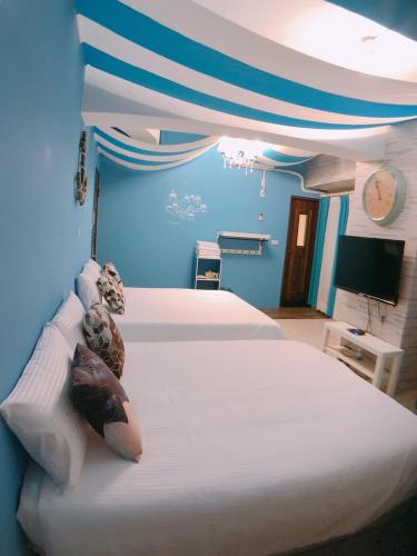 a blue room with two beds and a tv at Traveler Station R15 in Kaohsiung