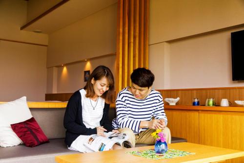two women sitting on a couch reading a magazine at Umino Ryotei Okinawa Nakamasou in Onna