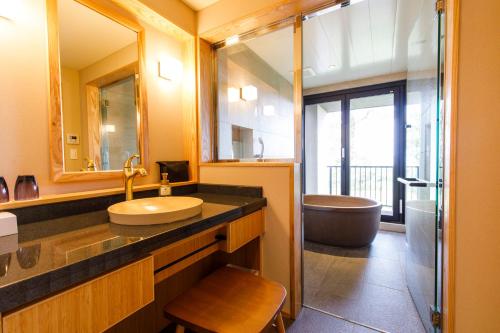 a bathroom with a sink and a tub and a mirror at Umino Ryotei Okinawa Nakamasou in Onna