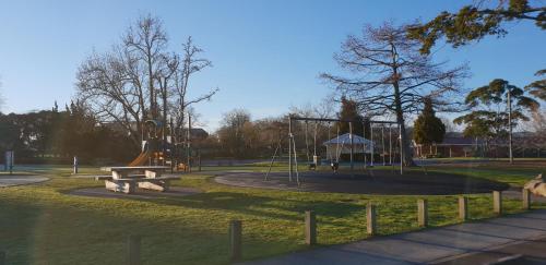 a park with a playground with a bench and a slide at Rose Apartments Unit 5 Central Rotorua- Accommodation & Spa in Rotorua