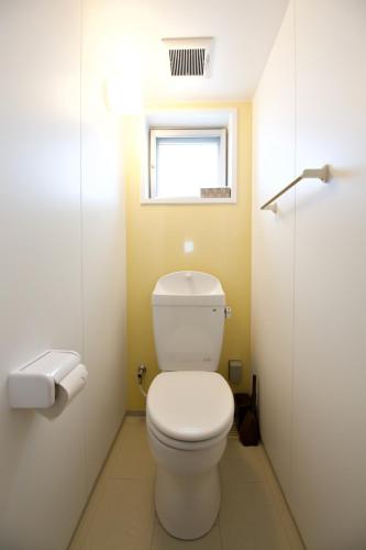 a bathroom with a white toilet and a window at Matsufuji 2F in Naha