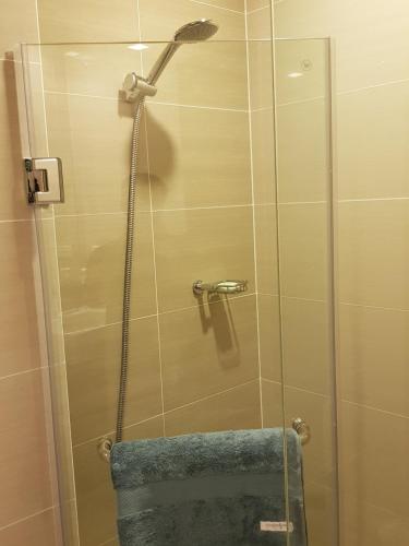 um chuveiro com uma porta de vidro e uma toalha azul em One Uptown Residences in Uptown BGC em Manila