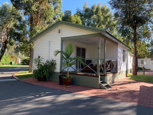 a small house with a porch with plants in it at Mandurah Caravan and Tourist Park in Mandurah