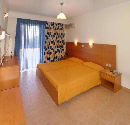 a bedroom with a bed with a yellow bedspread at Hotel Tigaki's Star in Tigaki