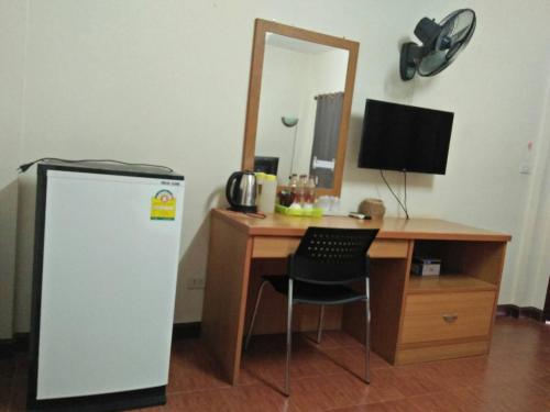 Cette chambre comprend un bureau avec un réfrigérateur et un miroir. dans l'établissement Sangthong Building, à Mae Chaem
