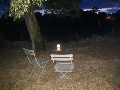 two chairs and a table with a candle on it at Au pied de l étang et du canal du Nivernais bazolles in Bazolles