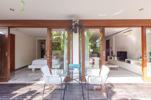 a dining room with a glass table and white chairs at AB Villa & Apartments in Seminyak