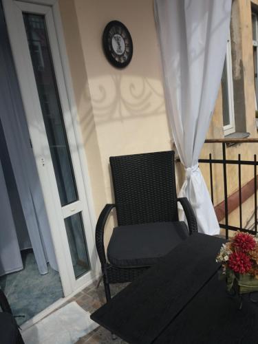 a chair sitting on a balcony with a clock on the wall at Apartment u Lidii in center of Kiev near railways station in Kyiv