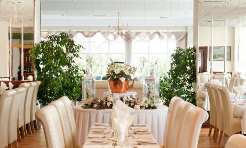 a dining room with white tables and chairs and plants at Majestic Hotel in Tramore