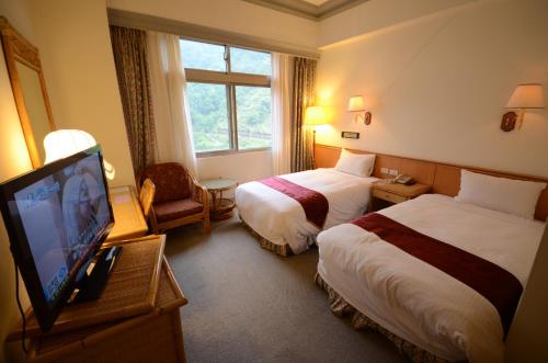 a hotel room with two beds and a flat screen tv at Dongpo Ti Lun Hotel in Xinyi