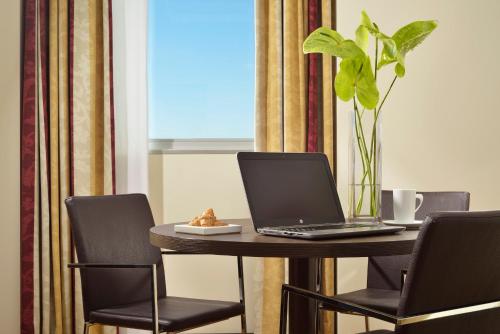 a table with a laptop and a plant on it at Hotel Diamante in Alessandria
