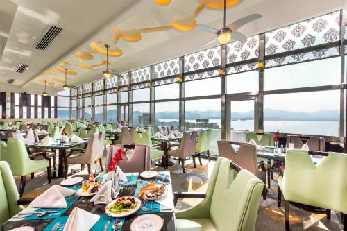 ein Esszimmer mit Tischen, Stühlen und großen Fenstern in der Unterkunft Huachen International Hotel in Hangzhou