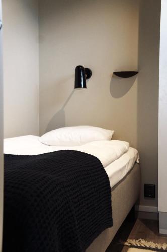 a bedroom with a bed with a black lamp on the wall at Destination Bokenäset in Uddevalla