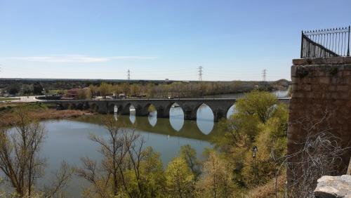 a bridge over a river with a bridge in the background at La casa del Duero in Tordesillas