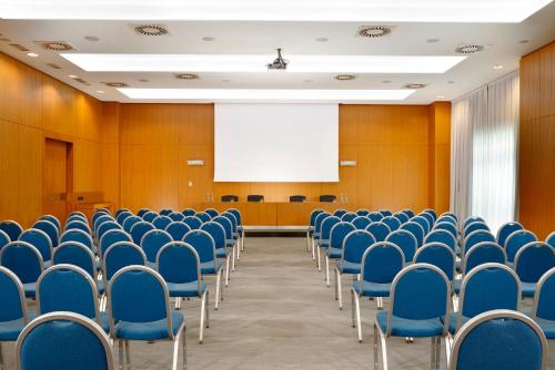 an empty conference room with blue chairs and a projection screen at Hotel Diamante in Alessandria