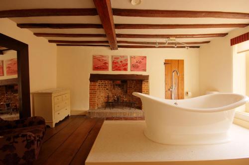 a bathroom with a bath tub in a room with a fireplace at Sutherland House in Southwold