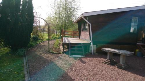 a house with a bench and a wooden deck at Chalet de vacances in Guisy