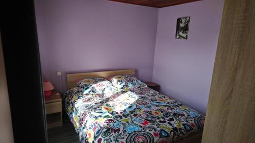 a bedroom with a bed with a colorful comforter at Chalet de vacances in Guisy