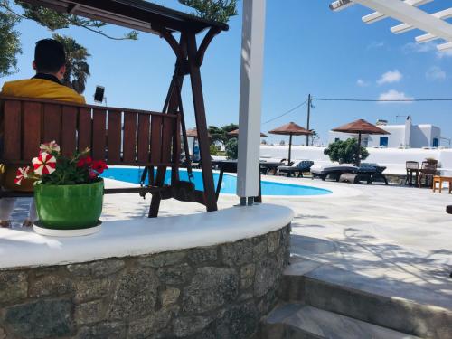 a man sitting on a bench next to a pool at Sofia Village in Mýkonos City