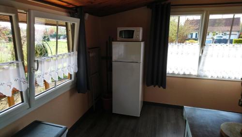 a room with a refrigerator and a microwave on top at Chalet de vacances in Guisy